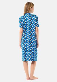 Vestido de manga corta azul y blanco con un diseño de zigzag. Tela ligera que cae hasta la rodilla, con aberturas laterales para mayor comodidad en los movimientos.