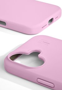 Różowe silikonowe etui na telefon z zaokrąglonymi krawędziami, otworem na aparat, wygrawerowanym logo z tyłu i otwartymi portami do łączności.