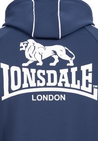 Marineblå hoodie med et hvidt løvegrafik og fed "Lonsdale London" tekst. Fremstillet af glat stof med en tætsiddende design og hætte.