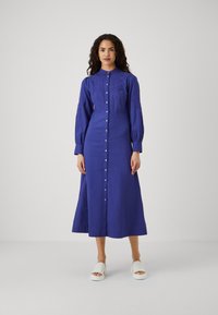 Vestito a maniche lunghe con bottoni di un blu vivace, con dettagli ricamati sulle maniche, realizzato in un tessuto testurizzato e con una vestibilità rilassata.