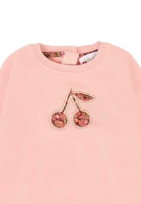 Felpa rosa con un design di ciliegia ricamato, con motivi floreali nel frutto e un colletto a costine con chiusura a bottone.
