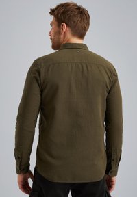 Camicia olive green a maniche lunghe, con bottoni, finitura texturizzata, vestibilità slim e bottone al colletto. Accenti scuri sulle maniche.