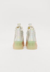 Zapatillas altas con un acabado metálico plateado, suelas de goma transparentes y acentos en degradado pastel. Presentan una marca en las lengüetas del talón.
