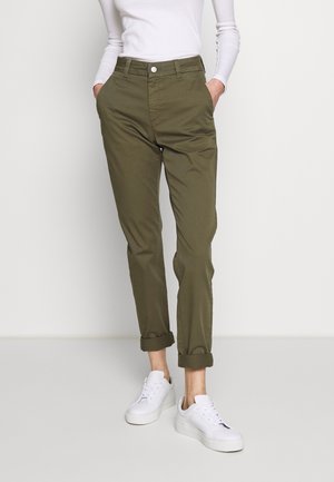 Khaki chinos med en tætsiddende pasform, der har lukning med knap, sidelommer, opkoblede manchetter og kombineret med hvide sneakers. Materiale i bomuldsblanding.