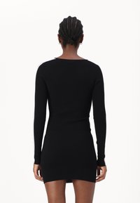 Schwarzes Langarmkleid in figurbetonter Design mit gerippter Textur, das kontrastierende weiße Streifen an den Ärmeln zeigt. Rückansicht dargestellt.