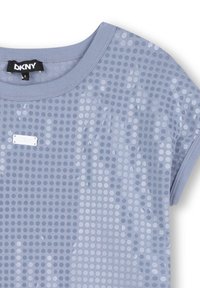 Chemise à manches courtes bleu clair avec un motif de points circulaires, fabriquée en tissu doux. Comprend une petite étiquette DKNY près de l'encolure.