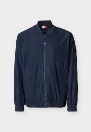 Geacă bomber bleumarin cu fermoar frontal, guler și manșete riburate, buzunare laterale și patch-uri cu logo-ul Tommy Hilfiger pe piept și mânecă.