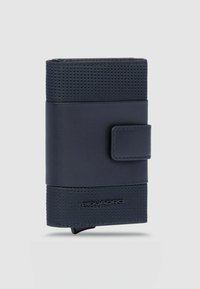 Marineblaue Geldbörse mit einer strukturierten Stoffoberfläche in der oberen Hälfte und glattem Leder in der unteren Hälfte, gesichert durch einen Lederriemen. Prägendes Logodetail am Boden.