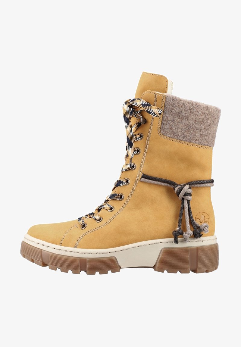 Botte de cheville à lacets en suède tan avec un col en feutre gris, des lacets à motifs et une semelle en caoutchouc épaisse et texturée. Agrémentée d'un détail décoratif en nœud.