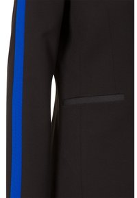 Chaqueta negra con una franja azul a lo largo de la manga, con una tela texturizada y un detalle de bolsillo discreto en el frente.