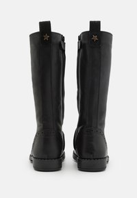 Bottes noires en cuir montantes avec une finition lisse, dotées de coutures décoratives, d'un accent en forme d'étoile et d'une fermeture éclair sur le côté pour un enfilage facile.