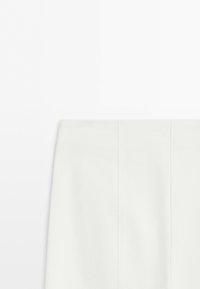 White high-waisted skirt with vertical seam details, shown from the waist down against a plain background.