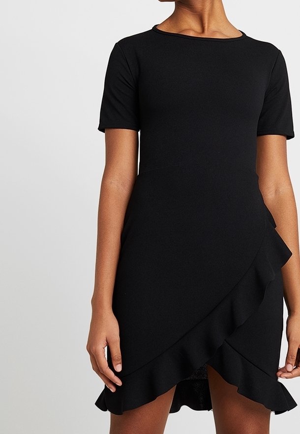 Femme portant une courte robe noire à manches courtes et un ourlet asymétrique à volants.