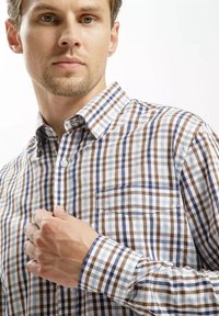 Koszula w kratkę z mieszanki bawełny, w niebieskie, brązowe i białe wzory. Kołnierzyk z zapięciem na guziki, długie rękawy i kieszeń na klatce piersiowej.