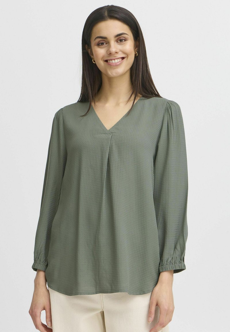 Blusa a maniche lunghe verde oliva con scollo a V, caratterizzata da una sottile trama, maniche arricciate e un taglio rilassato.