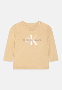 Beiges Langarmshirt aus weichem Stoff mit rundem Kragen, Druckknopf und weißem gedrucktem Logo: "Calvin Klein Jeans."
