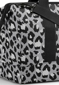 Bolsa de viaje con estampado de leopardo que presenta una combinación de colores en gris y negro, fabricada con un material duradero y con correas de tejido negro para un fácil transporte.