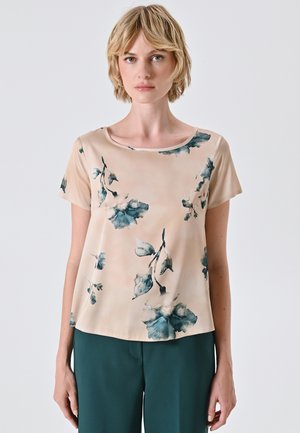 Blusa a stampa floreale in beige chiaro con accentuazioni blu-verdi, maniche corte e scollo rotondo. Tessuto leggero e liscio con una vestibilità rilassata.