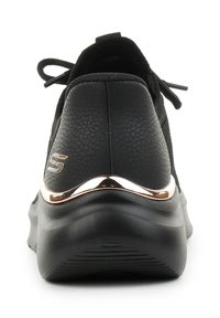 Zapatilla negra con parte superior texturizada, tacón redondeado y un acento metálico en color rosa oro en la suela, con cierre de cordones y acolchado en el collar.