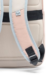 Könnyű hátizsák, bézs textúrájú testtel, rózsaszín kiegészítőkkel, lélegző pántokkal és fekete hardverrel a biztonságos állításhoz.