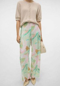 Cardigan corto a maniche corte beige, lavorato a maglia, con chiusura a bottoni; pantaloni palazzo a righe verdi, rosa e beige; scarpe beige a punta; piccola borsa color crema.