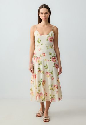Bloemen midi-jurk met dunne bandjes, voorzien van een lichtcrème achtergrond met roze pioenrozen en groene bladeren. Soepele, vloeiende stof.
