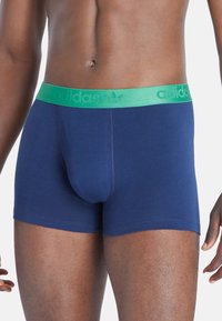 Boxer in cotone blu con vita elastica verde che presenta il logo Adidas. Tessuto morbido, design aderente, lunghezza fino alla metà della coscia.