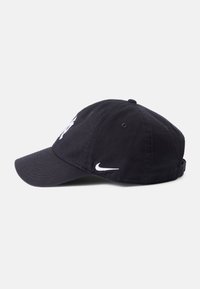 Gorra de béisbol negra hecha de tela, con un logo bordado en blanco en la parte frontal y un Swoosh blanco en el lado; correa ajustable en la parte posterior.
