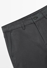 Ciemnoszare spodnie wykonane z bawełnianej mieszanki o fakturowanym wykończeniu. Posiadają zapięcie na guziki, szlufki na pasek oraz boczne kieszenie.