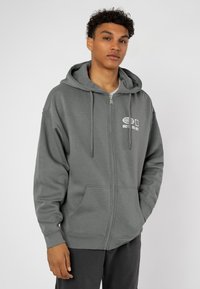 Gray zip-up hoodie with a front pocket, drawstring hood, and white printed text. Made of a soft, smooth fabric with ribbed cuffs.