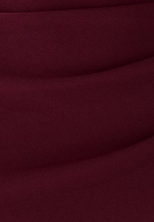 Bordeaux-stof med en glat tekstur, der har let drapering og bløde bølger, hvilket skaber dybde gennem variationer i lys og skygge.