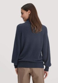 Dunkelblauer Strickpullover mit hohem Kragen, Ballonärmeln sowie gerippten Bündchen und Saum. Besitzt eine weiche Textur und eine lockere Passform.