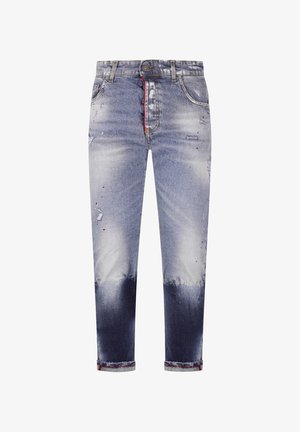 Vaqueros ajustados de hombre en denim azul con zonas descoloridas y desgastadas, con un detalle rojo en el interior de la bragueta y puños remangados.