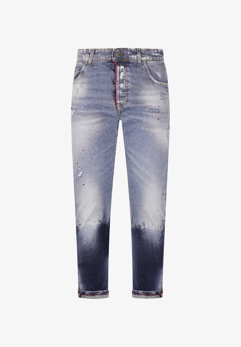 Vaqueros ajustados de hombre en denim azul con zonas descoloridas y desgastadas, con un detalle rojo en el interior de la bragueta y puños remangados.