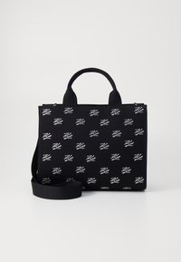 Musta kangaskassi, jossa toistuva valkoinen logokuvio. Suorakulmainen muoto, päällinen vetoketjulla, kaksinkertaiset kahvat ja säädettävä hihna.