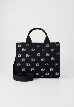 Borsa tote nera in tessuto, con un motivo ripetuto di loghi bianchi. Forma rettangolare con cerniera superiore e doppi manici, più una tracolla regolabile.