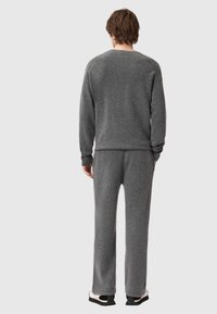 Szara bluza z polaru i dopasowane spodnie, cechujące się luźnym krojem, ściągaczami na rękawach oraz miękką fakturą, noszone z czarno-białym obuwiem.