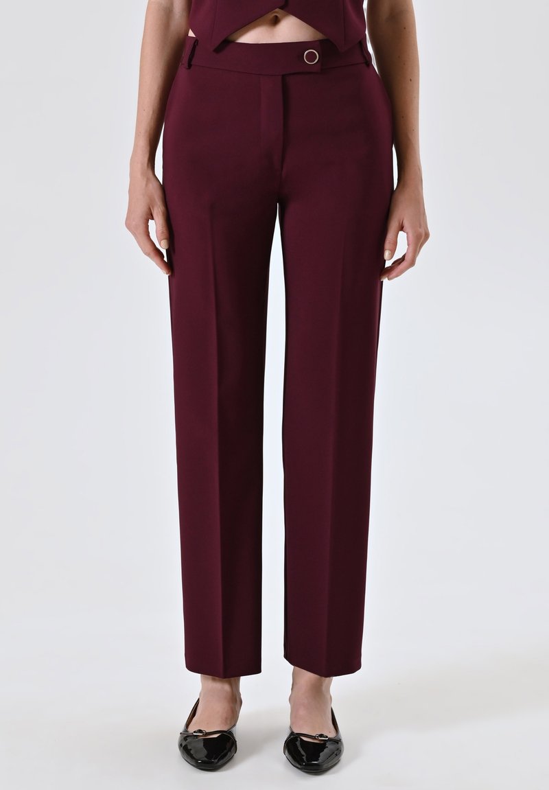 Pantaloni sartoriali bordeaux con vestibilità dritta, dotati di un dettaglio con bottone in vita, realizzati in tessuto liscio e abbinati a ballerine nere.