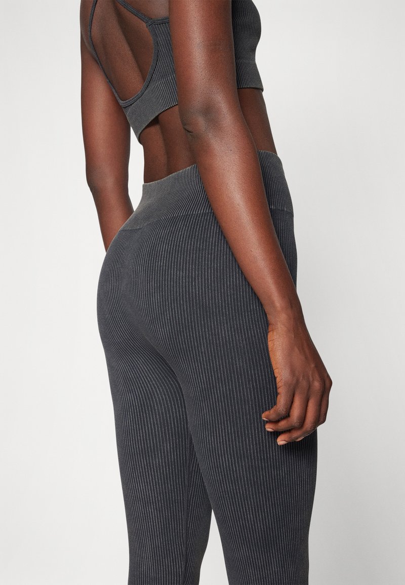 Dunkel gestreifte Leggings mit hoher Taille und strukturierter Oberfläche, kombiniert mit einem passenden, cropped Top mit einem Ausschnitt im Rücken.