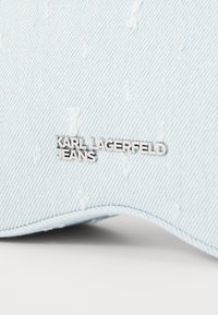 Svetlomodrá denímová čiapka s opotrebovanou textúrou a strieborným logom s nápisom "KARL LAGERFELD JEANS" vpredu. Zakrivený šilt.
