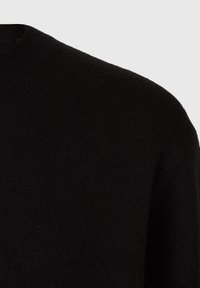 Czarny wełniany sweter z okrągłym dekoltem, miękką teksturą i delikatnymi włóknami, prezentujący lekko luźny krój i minimalistyczny design.