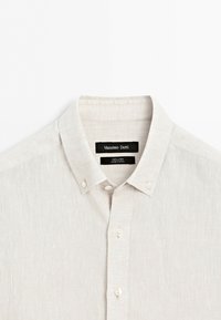 Light beige linen button-up shirt with button-down collar, front buttons, and Massimo Dutti label, shown against a white background.