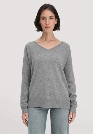 Grijze v-halstrui met lange mouwen, gemaakt van zachte stof, met ribgebreide manchetten en zoom, gecombineerd met lichtblauwe jeans.