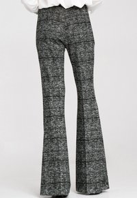 Dzwony z teksturowanej czarno-białej tkaniny, z wysokim stanem i szerokimi nogawkami.