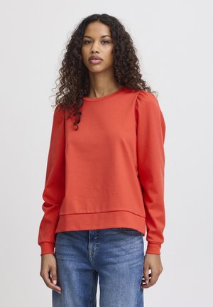 Red, long-sleeve sweatshirt with a round neckline and gathered details at the shoulders. Made of soft, textured fabric, paired with blue jeans.