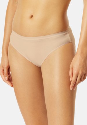 Woman wearing smooth, beige bikini-style underwear, showing midriff and upper thighs against a plain light background.