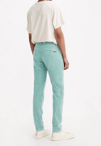 Ljusblå chinos i bomull med slim fit, med bakfickor och en loggobadge. Kompletterad med en enkel vit t-shirt och sneakers.