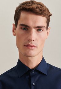 Camicia blu navy abbottonata realizzata in tessuto liscio, dotata di colletto classico e bottoni a contrasto, con una silhouette adatta.