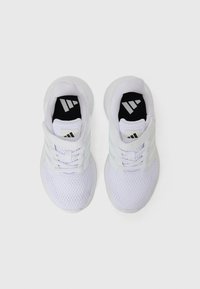 Adidași albi, cu o parte superioară din plasă, accente cu trei dungi și guler căptușit. Tălpile interioare negre au detalii cu logo argintiu.