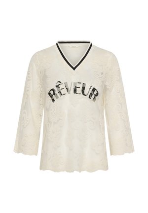 Haut à manches longues en dentelle crème avec col en V rayé noir et blanc et "RÊVEUR" inscrit en lettres noires délavées sur la poitrine.